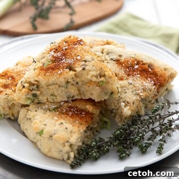 Savory almond flour scones on a white plate with some fresh thyme sprigs.
