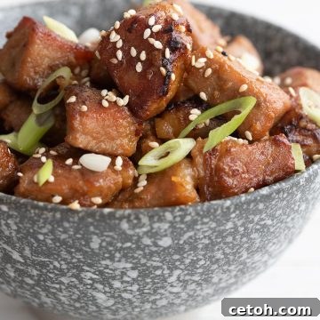 Close up shot of honey garlic pork bites in a gray bowl.