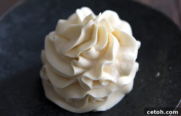 Rich keto vanilla frosting beautifully piped into a dark bowl, ready for cake decoration.