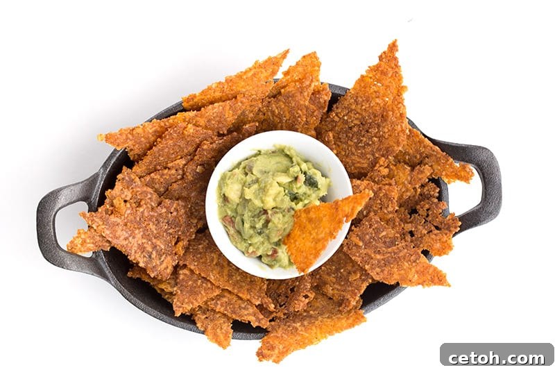 Top-down photo of perfectly crispy low-carb tortilla chips served with fresh guacamole.