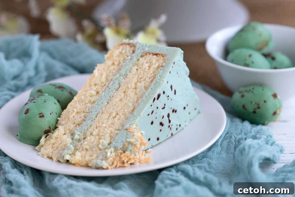 A close-up shot of a perfect slice of Robin's Egg Cake on a white plate, showing the blue frosting and pale cake layers.