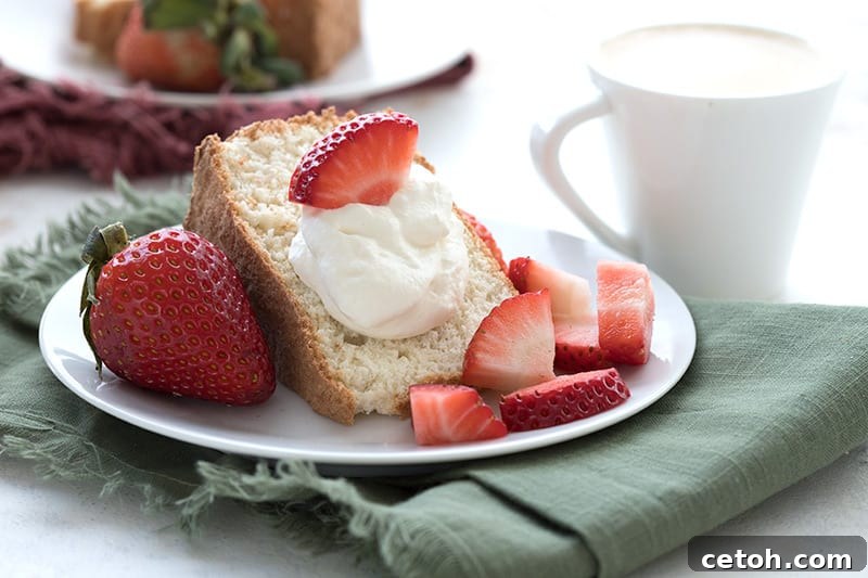 A slice of light and airy Keto Angel Food Cake with berries and cream.