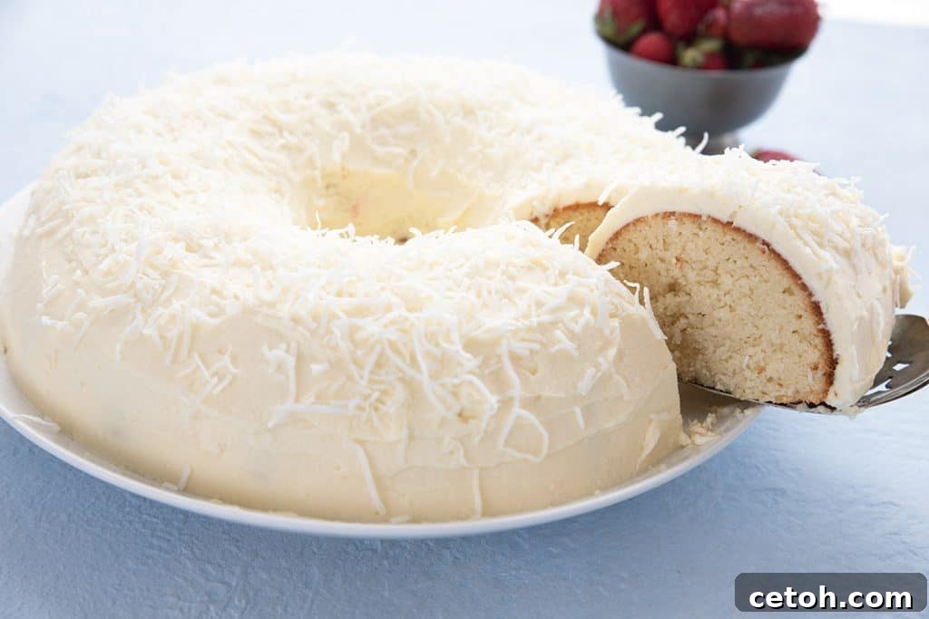 A beautiful sugar-free keto coconut cake on a white plate with a perfect slice being lifted out of it.
