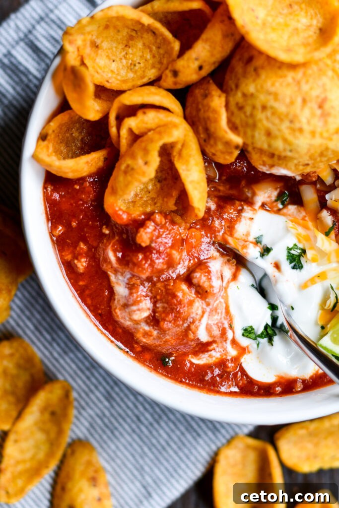 A steaming pot of Dad's Southern Homemade Chili, rich with meat and spices, is stirred gently on the stovetop, ready to be enjoyed as a warming family meal.