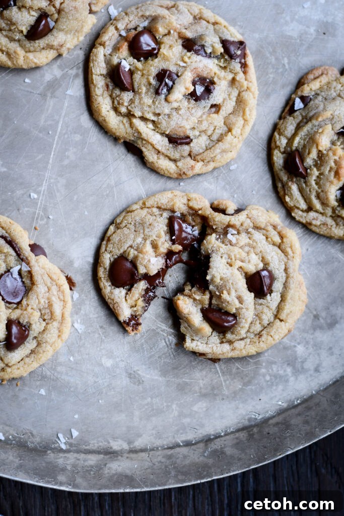 A tempting stack of golden-brown chocolate chip cookies with perfectly melted chocolate, presented on a rustic wooden board.