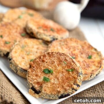 Crispy Air Fryer Eggplant on white tray over a burlap napkin, with eggplant, garlic, and parmesan in the background.