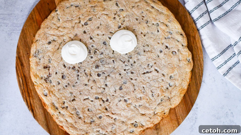 Use a large round piping tip to pipe two large white circles for the eyes near the top center of the cookie, then add pupils with black frosting.