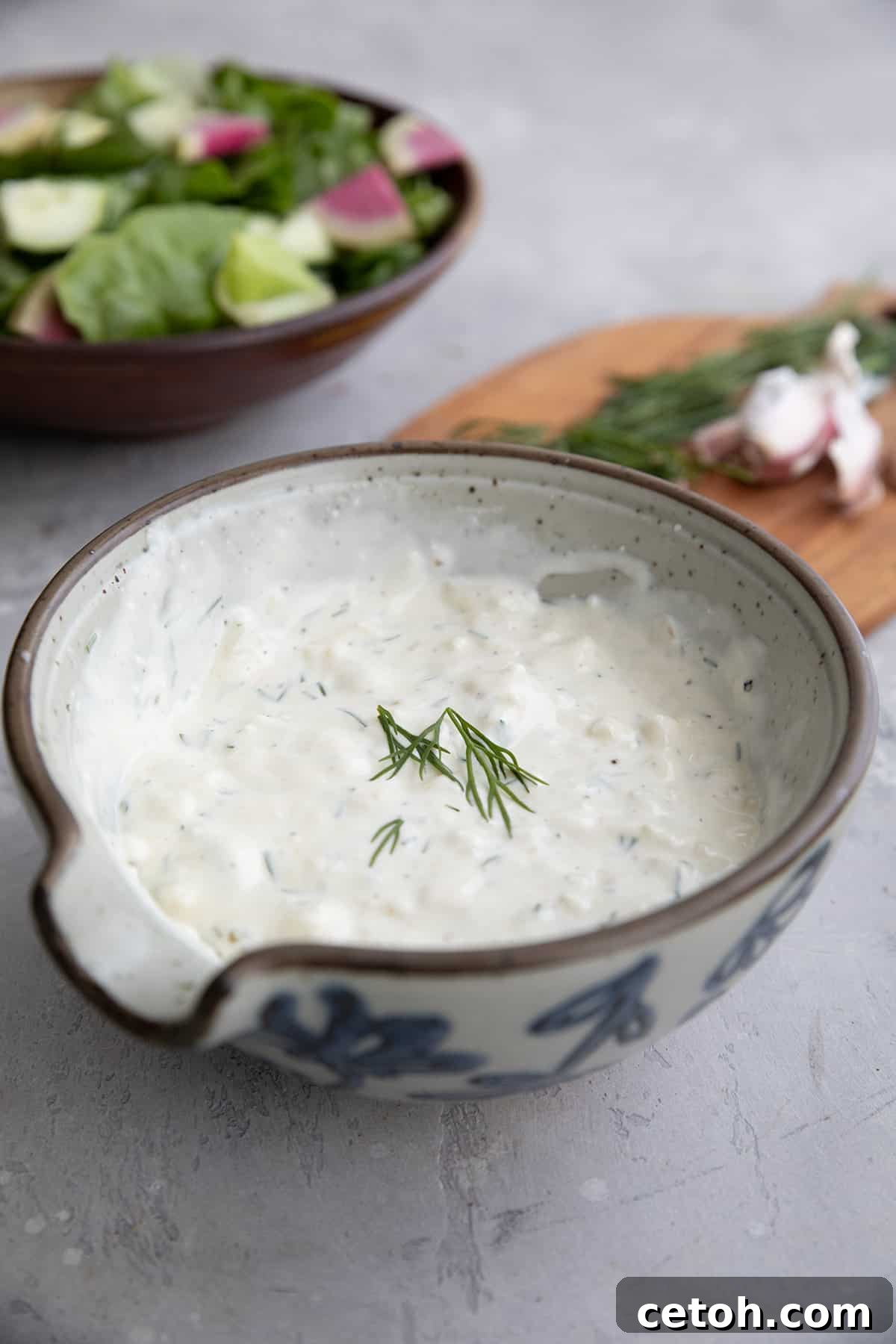 Feta Dressing iin a gray bowl in front of a bowl of salad.