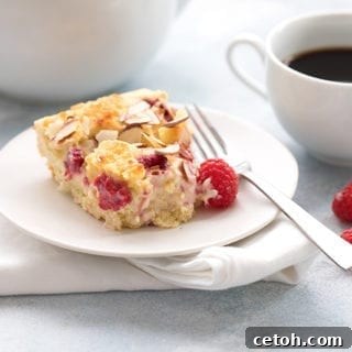 A slice of cream cheese coffee cake on a plate with raspberries