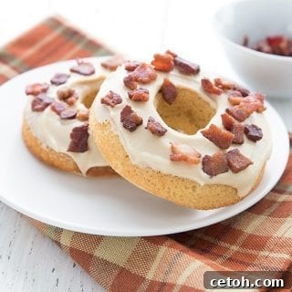 A white plate with two keto maple bacon donuts over a plaid napkin