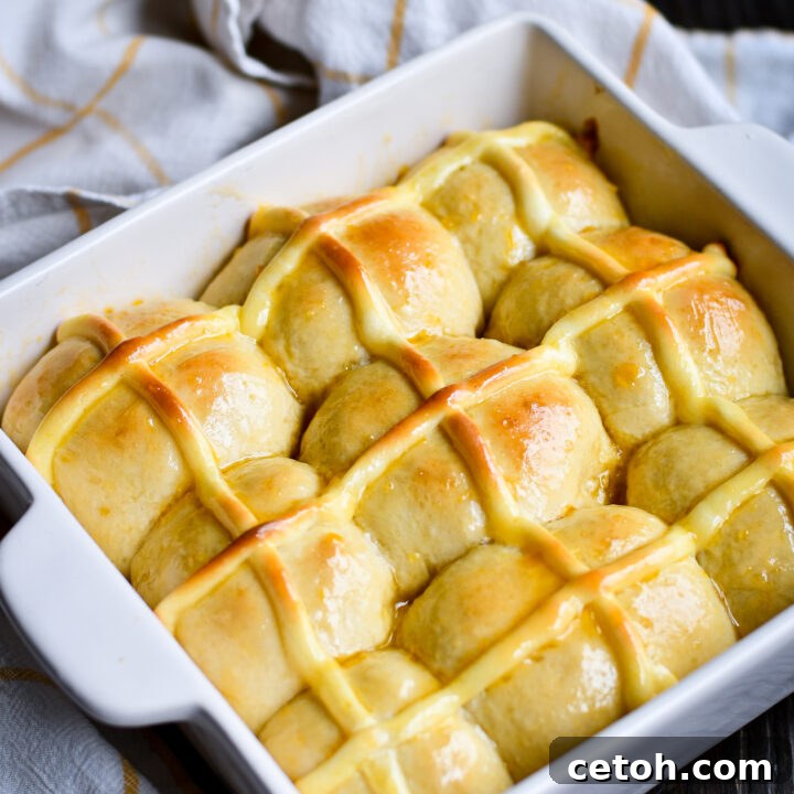 Love hot cross buns but not a fan of raisins? Try this soft & fluffy homemade hot cross buns recipe with warm cinnamon, an apricot glaze, and a cheesecake-style pastry cream cross baked right in! Perfect for Easter brunch or a sweet treat anytime.