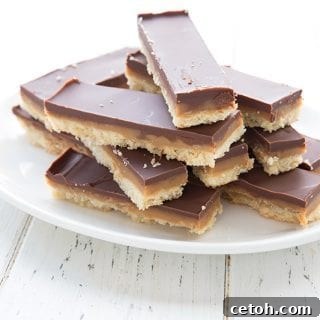 A white plate full of cut up homemade Twix bars on a white table.