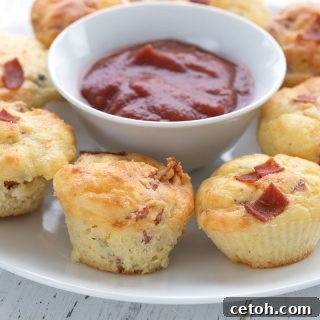 Close up shot of mini keto pizza muffins, golden brown with melted cheese and pepperoni visible.