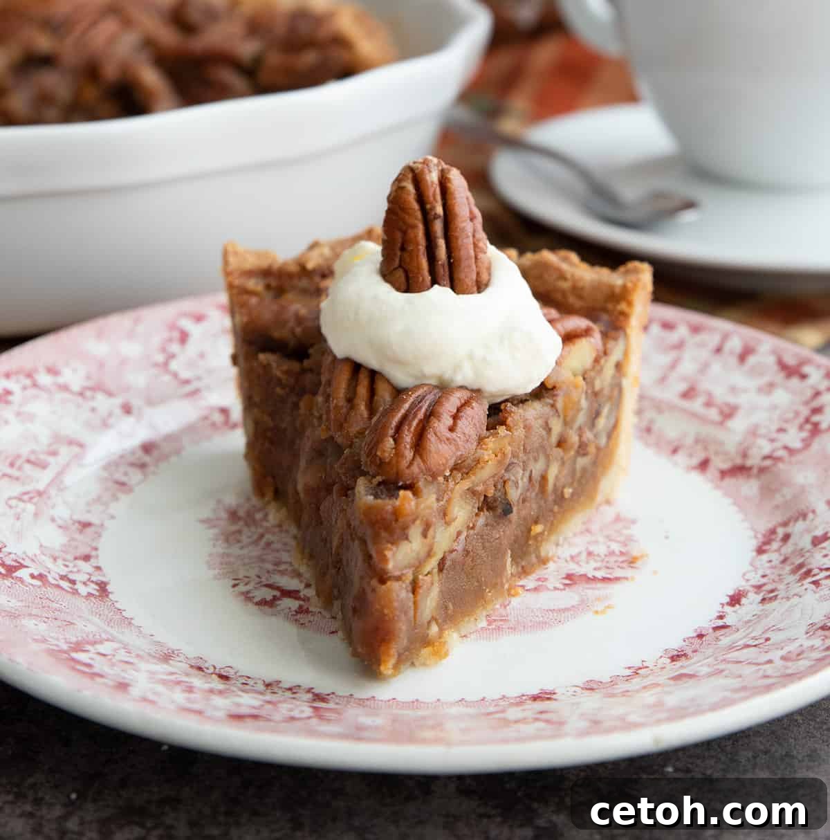 A slice of keto pecan pie sitting on a plate with whipped cream on top.