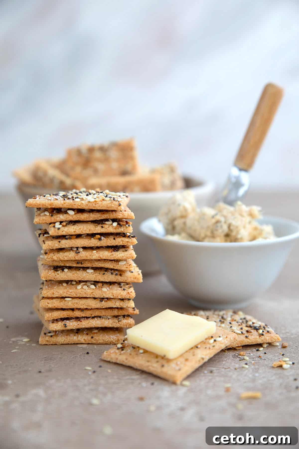 A stack of keto crackers on a brown table with Boursin cheese beside it.