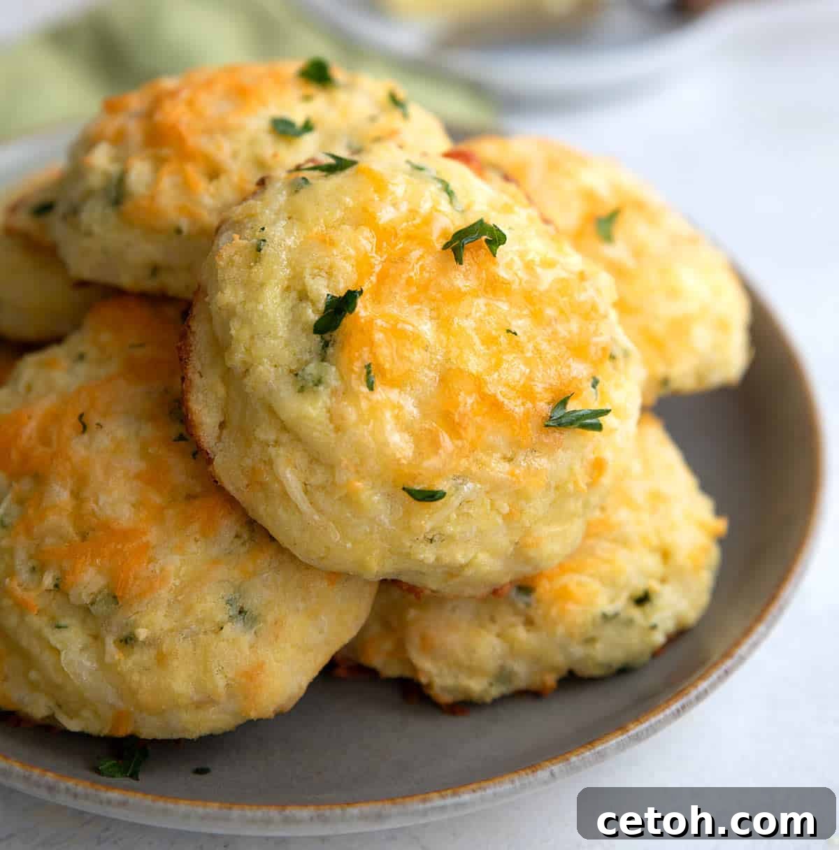 Keto Cheese Biscuits piled up on a grey plate on a white table top.