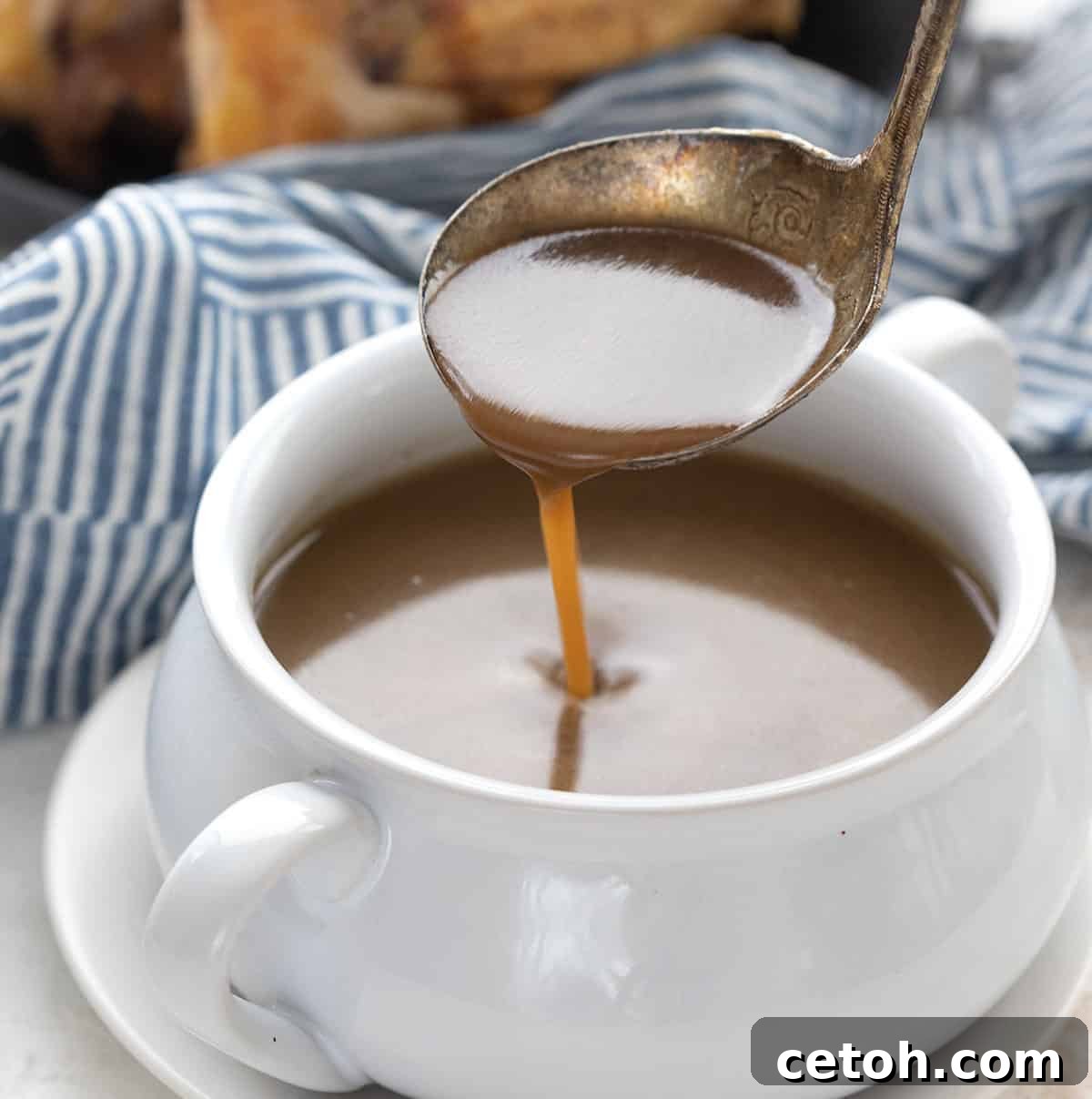 A ladle drizzling keto gravy into a white bowl.