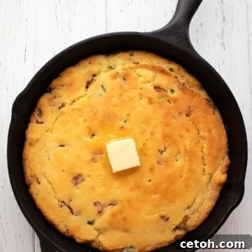 Top down image of keto cornbread in a skillet on a white wooden table.