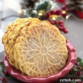 Keto pizzelle in a red bowl, surrounded by holly and pine cones, with fairy lights in the background, signaling festive deliciousness.