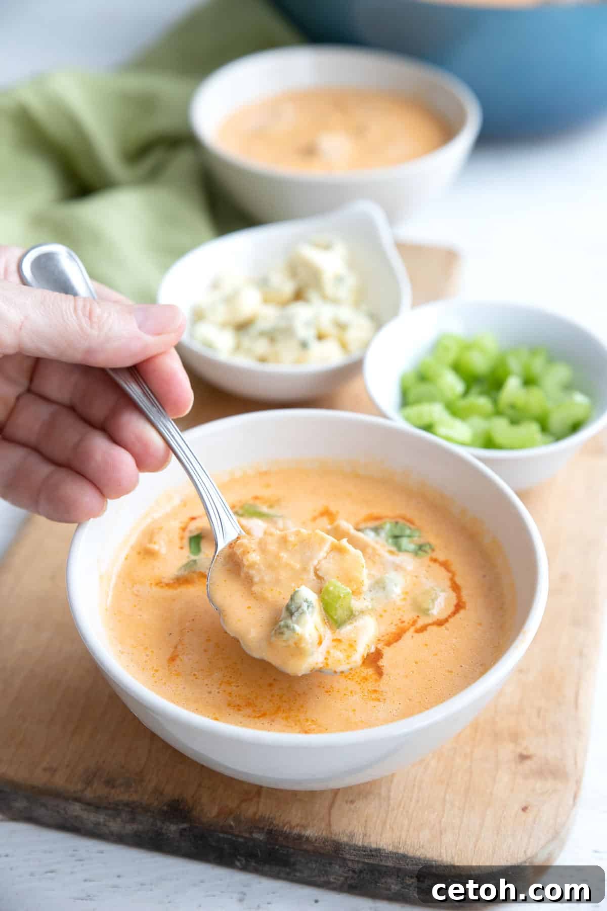 A spoon dipping into a rich and creamy bowl of Buffalo Chicken Soup, inviting you to enjoy its warmth and flavor.