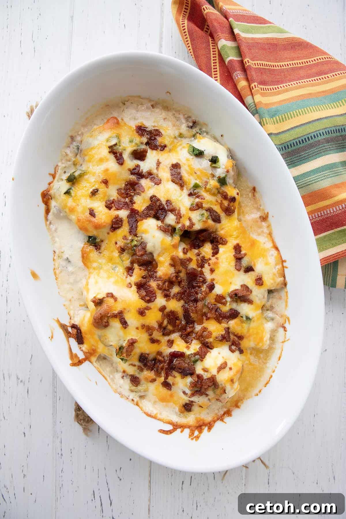 Top-down image of bubbling Jalapeño Popper Chicken baked in a ceramic oval dish, ready to be served.