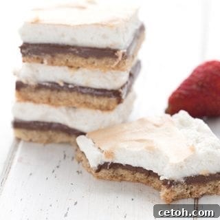 A stack of keto s'mores on a white table, with one s'mores bar in front and a strawberry in behind.
