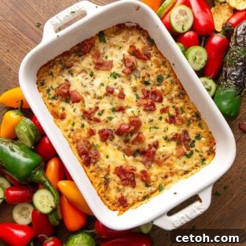 Top down image of Caramelized Onion Dip on a brown table, surrounded by vegetables.