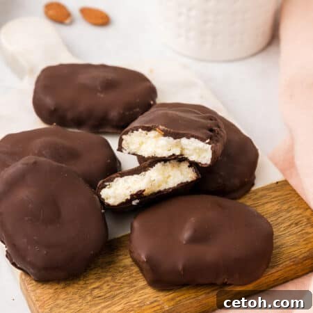 A pile of Keto Almond Joy Easter Eggs on a wooden cutting board with one broken open.
