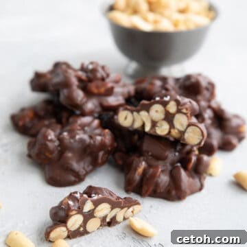 Keto Peanut Clusters piled up on a table with a bowl of peanuts in the background.