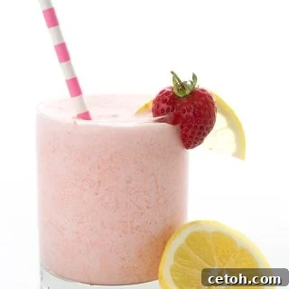 A glass full of keto strawberry frosted lemonade with a stripped pink straw.