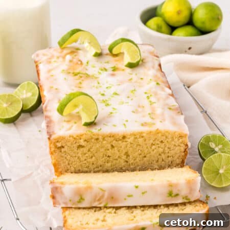 A loaf of Keto Key Lime Pound Cake on a wire cooling rack with several slices cut out in front.