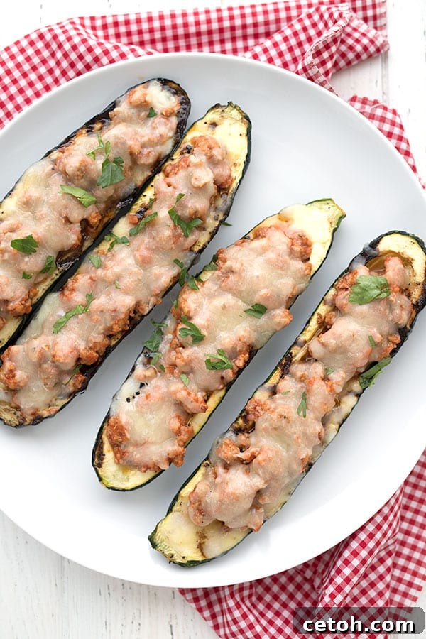 Top down photo of stuffed zucchini boats on a white plate over a red checked napkin