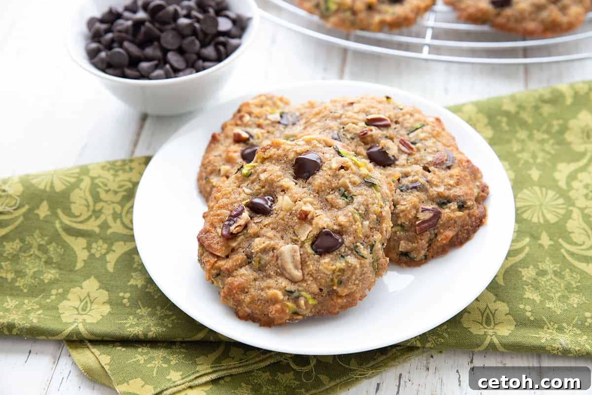 Three keto zucchini cookies on a white plate over a green patterned napkin.