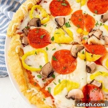Top view of a keto pizza topped with pepperoni, mushrooms and banana peppers