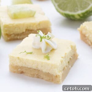 Close up shot of a keto key lime bar with whipped cream and lime zest on top.