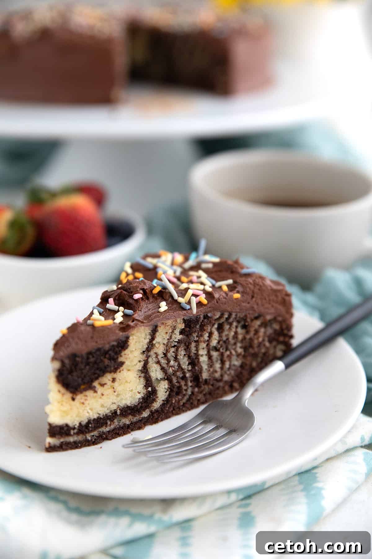 A slice of Keto Zebra Cake on a white plate with a fork.