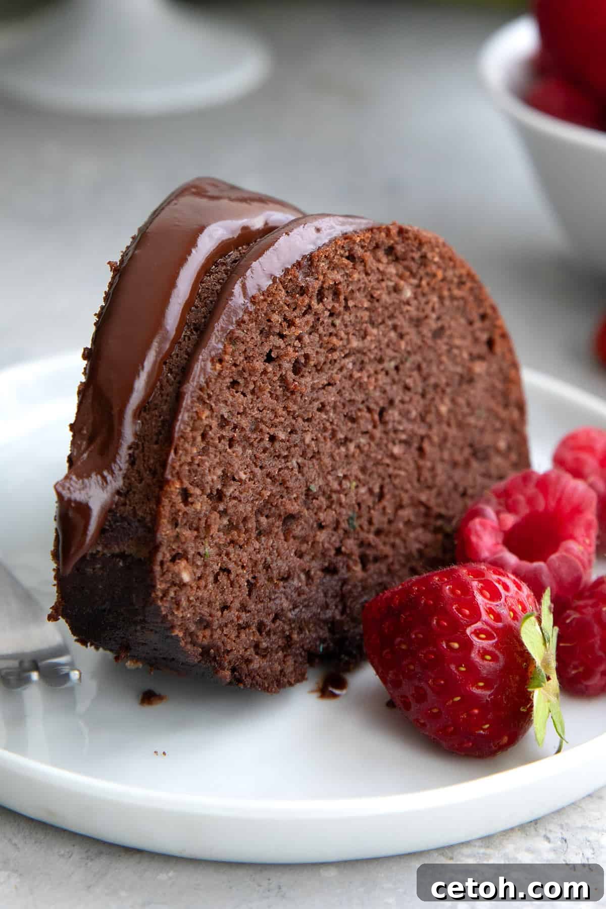 A slice of Keto Chocolate Zucchini Cake on a white plate with fresh berries.