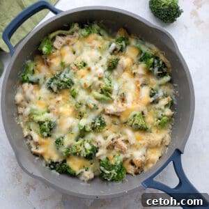 Creamy Keto Chicken Broccoli Bake 2 Top down image of cheesy Chicken Broccoli Casserole in a skillet on a white table, showcasing the rich texture and golden cheese.
