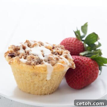A coffee cake keto muffin on a white plate with strawberries.