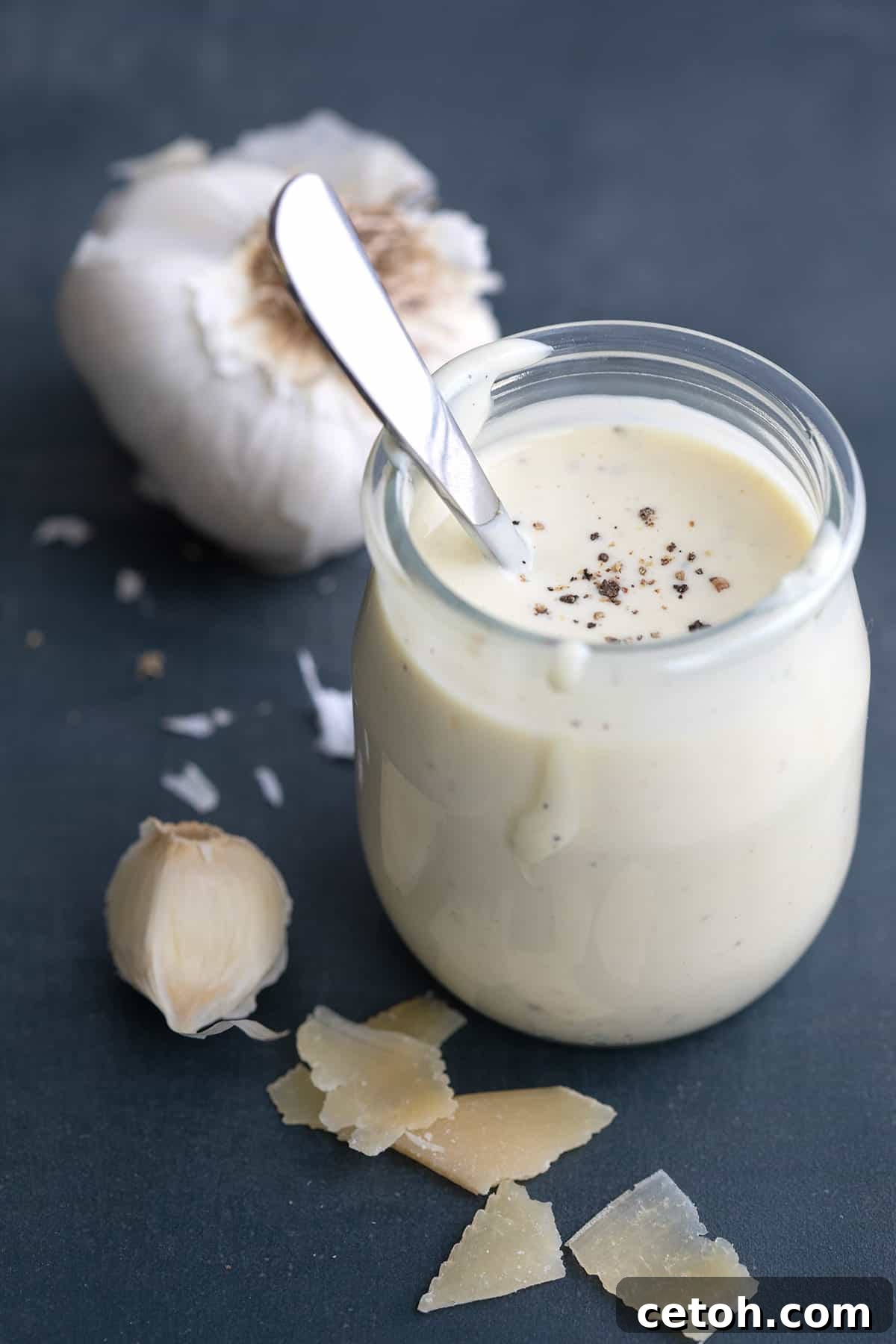 Elevate Your Keto Salads with Top Dressing Choices 5 A jar of Easy Caesar Dressing surrounded by garlic and Parmesan.