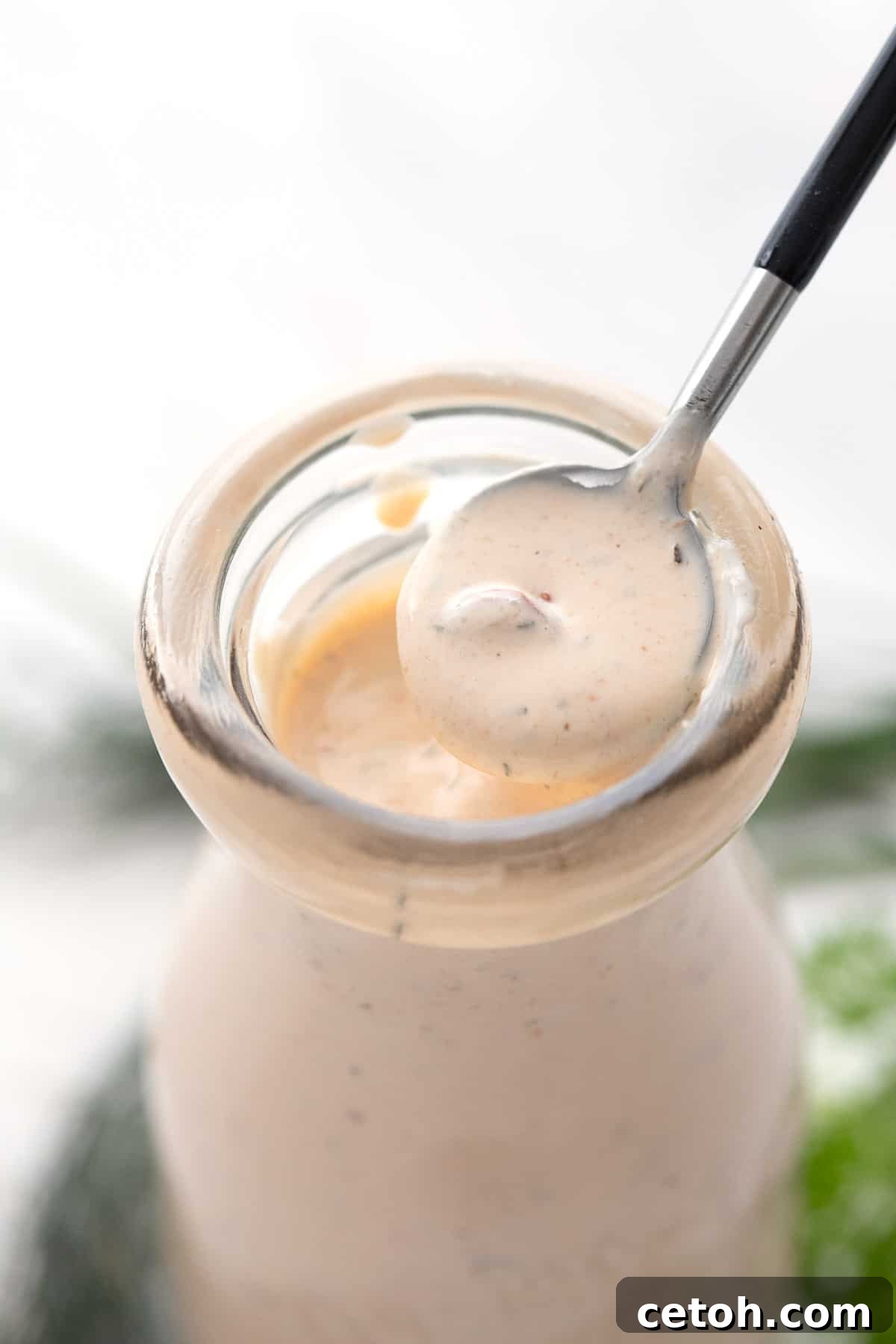Elevate Your Keto Salads with Top Dressing Choices 4 Close up of a spoon lifting some Chipotle Ranch Dressing out of a glass bottle.