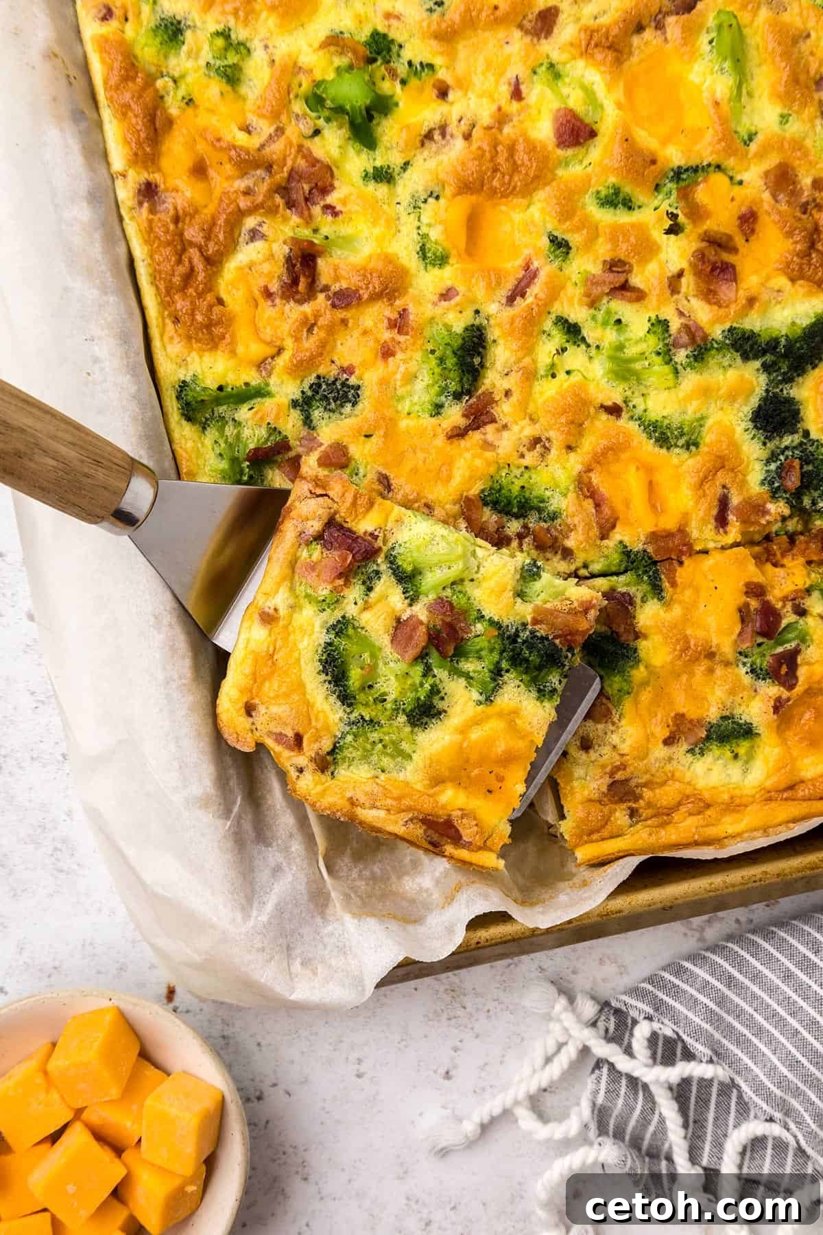 Top down image of Sheet Pan Frittata with a piece cut out and sitting on a spatula.