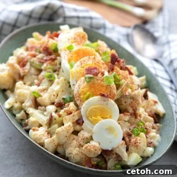 Creamy Cauliflower Potato Salad 2 Creamy Keto Cauliflower Potato Salad in a vibrant green oval serving dish, beautifully garnished with slices of hard-boiled egg and a sprinkle of paprika.