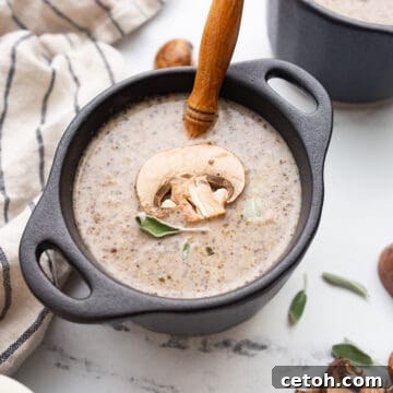 Keto Mushroom Soup in a black bowl with a spoon resting in it.