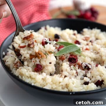 Wholesome Cauliflower Pilaf 2 Keto Rice Pilaf in a black bowl with a spoonful being lifted out of it.