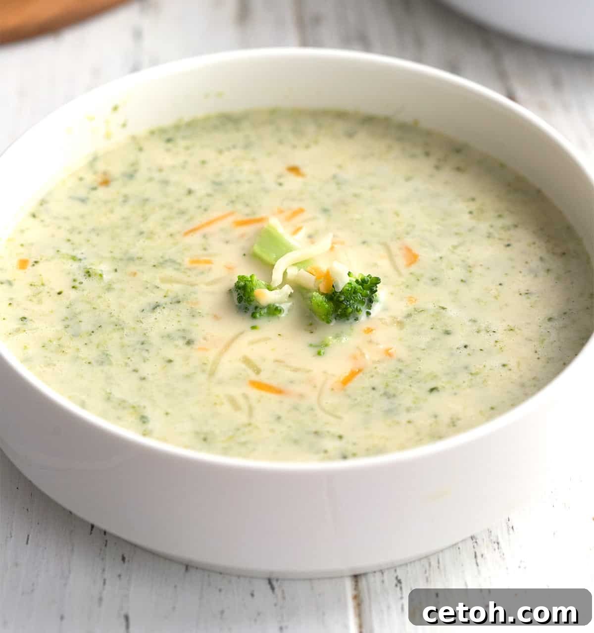 A white bowl brimming with rich Keto Broccoli Cheese Soup, a classic comfort food reimagined for low-carb diets.