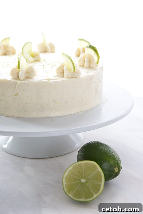 Keto Tequila Lime Delight 3 The whole keto margarita cake on a cake platter with two limes in front.