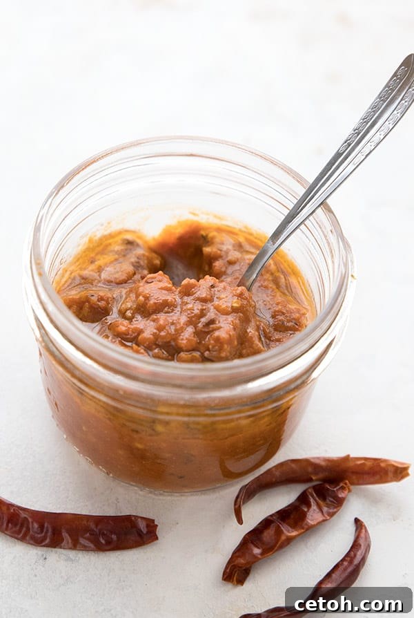 A close-up shot of a glass jar filled with vibrant red homemade harissa paste, showcasing its rich texture.