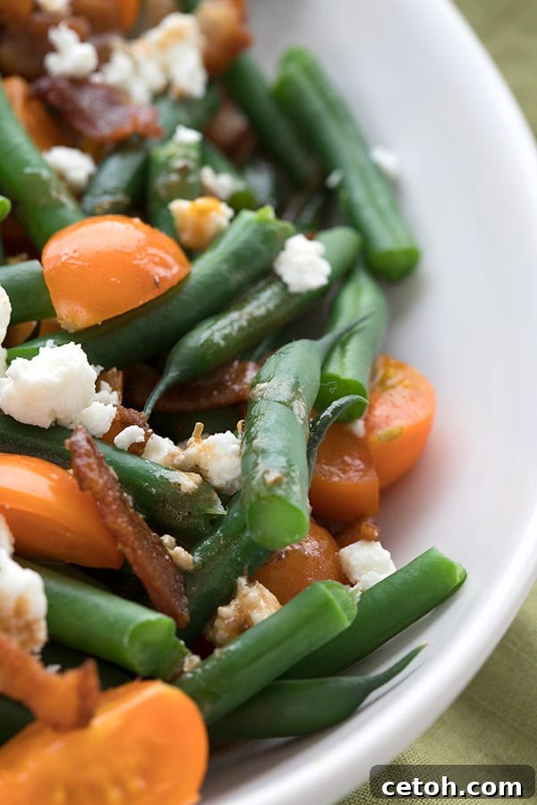A delicious close-up view of the Keto Green Bean Salad, highlighting the perfectly blanched green beans, vibrant cherry tomatoes, and crispy bacon pieces. The salad is drizzled with a light vinaigrette.