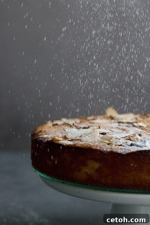 Powdered sweetener being dusted down over keto almond ricotta cake